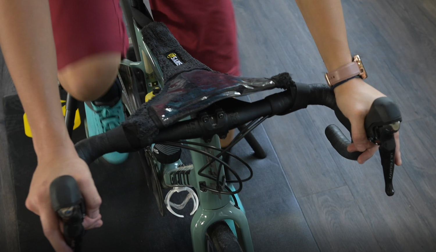 Saris Sweat Guard draped over bike frame on trainer — showing full-frame sweat coverage