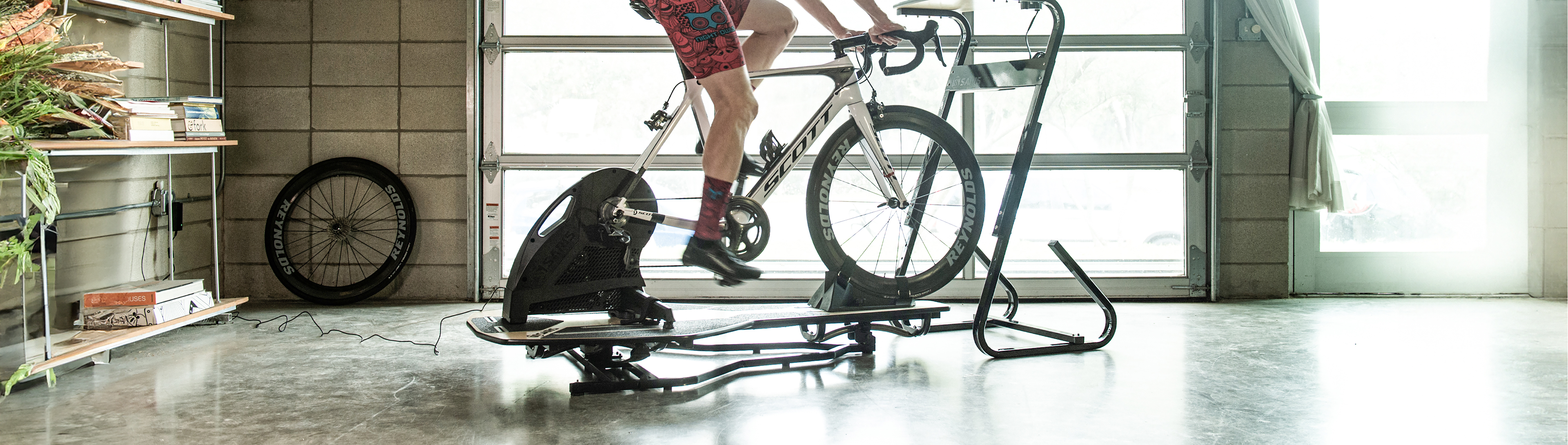 Cyclist on a Scott road bike training on Saris MP1 Nfinity platform with H3 smart trainer in a home garage