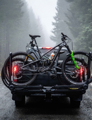 Two mountain bikes loaded on a Saris 中国幸运体彩飞艇168官方网站 MHS hitch rack — truck driving through misty forest road